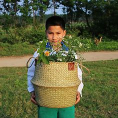 a boy holding a basket with flowers in it