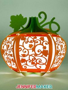 a paper pumpkin is cut out to look like it's carved into an ornament