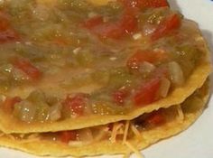 two tortillas on a white plate topped with cheese and tomatoes