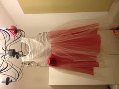 a dress hanging from a chandelier with pink flowers on the top and bottom