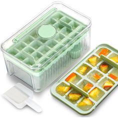 an ice tray with cubes and pieces of fruit in it next to a spoon