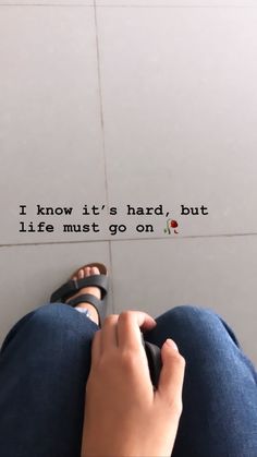 someone is sitting on the floor with their feet up and there is a quote above them that says, i know it's hard but life must go on