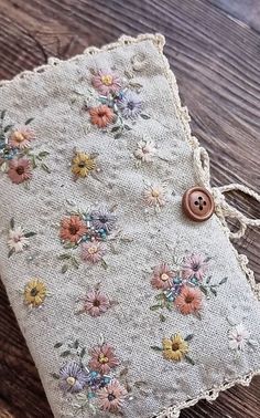 an old piece of cloth with flowers on it sitting on a wooden table next to a button