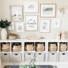 a dining room table with some baskets on top of it and pictures above the table