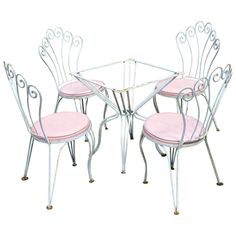 a set of four chairs and a table with pink cushions on it, all in different shapes and sizes