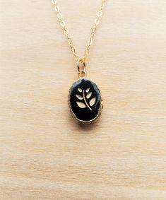 Minimal leaves on a black onyx pendant. A black onyx stone is gold-plated and paired with a dainty gold-filled chain. Gold-filled chains contain a minimum of 5% gold to increase durability against wear, heat and water. The gold chain comes with a spring ring clasp. A protective layer of resin is cured over the design. The pendant is approximately 1/2 inch tall by 3/8 inch wide and 3/16 inch thick. Since the exact shape of each pendant is unique, sizes can vary. These necklaces are available in 16/18/20 inch lengths. Perfect minimal design to layer necklaces. At this time, only gold is offered.  Basic Jewelry Care: -Take off your jewelry when showing, swimming, exercising, etc. -Avoid abrasive surfaces, like sand. -Regularly clean your jewelry with a soft damp cloth and dry with a clean tow Black Brass Pendant Necklace, Black Brass Jewelry With Adjustable Chain, Black Gold-plated Adjustable Chain Jewelry, Handmade Black Brass Necklace, Gold Onyx Necklace With Adjustable Chain, Gold Brass Jewelry With Black Enamel, Black Round Pendant Necklace, Gold Plated, Black Enamel Oval Necklace As Gift, Black Enamel Oval Necklace For Gift