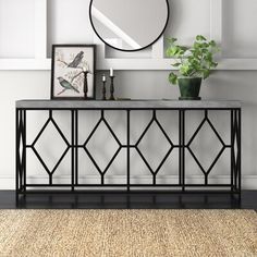 a black metal console table with a round mirror above it and plants on the side