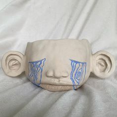 a ceramic mask with blue paint on it's face sitting on a white sheet