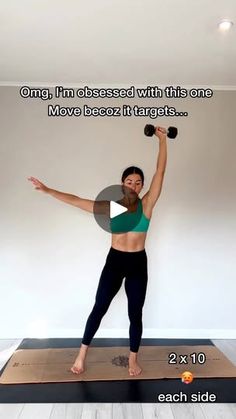 a woman standing on top of a yoga mat holding two dumbbells in her right hand