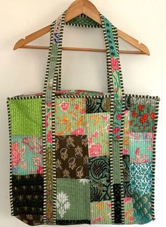 a multicolored patchwork bag hanging on a wooden hanger with a white wall in the background