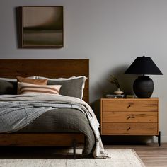 a bed sitting next to a nightstand with a lamp on top of it in a bedroom