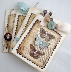 three tags with butterflies on them are sitting next to each other, one has a button and the other has a bow