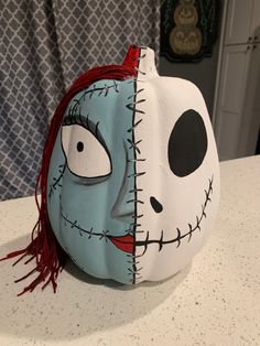 a white pumpkin with a blue face and red hair