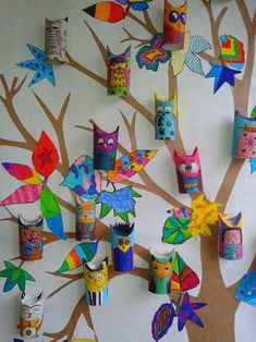 a tree with many colorful owls hanging from it's branches and on the wall