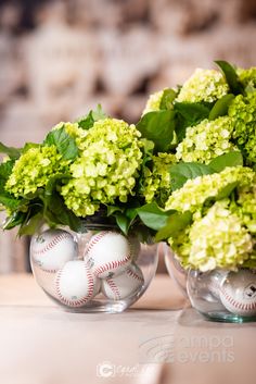 two vases filled with green flowers and baseball balls