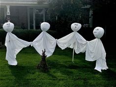 three white ghost decorations in front of a house