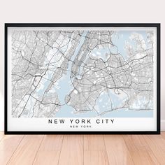 a framed map of new york city, usa in white and black on a wooden floor