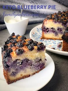 a blueberry pie is on a plate next to another slice