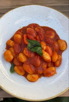 a white plate topped with tomato sauce and green leafy garnish on top of it