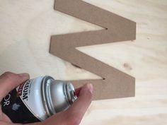 someone is holding a can of soda in front of a cut out arrow on a wooden table