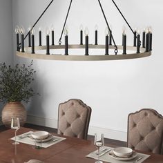 a chandelier hanging over a dining room table with place settings on the plates