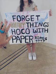 a woman holding up a sign that says forget it shiny things hoco with paper rings