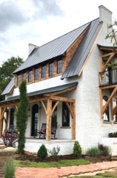 a large white house with wood trim and windows on the front porch is surrounded by greenery