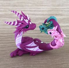 two toy dragon figurines sitting next to each other on a wooden table top