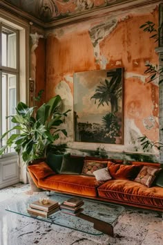 a living room with an orange couch and large painting on the wall above it's glass coffee table