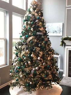 a decorated christmas tree with green and gold ornaments in a living room next to a fireplace