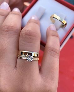 a woman's hand with two gold rings in front of her and an empty ring box