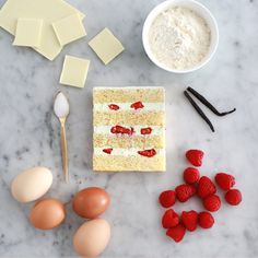 ingredients to make strawberry shortcakes laid out on a marble counter top, including eggs, butter and strawberries