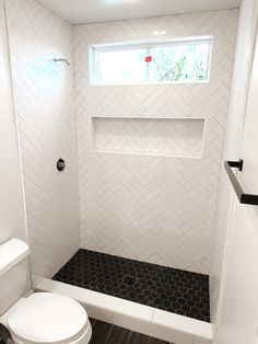 a white toilet sitting next to a window in a bathroom on top of a hard wood floor