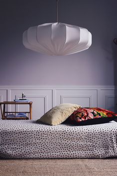 a bed sitting in a bedroom next to a wall with a lamp hanging above it