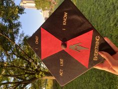 a person holding up a black and red graduation cap