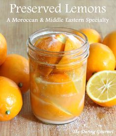 a jar filled with lemons sitting on top of a wooden table next to sliced lemons