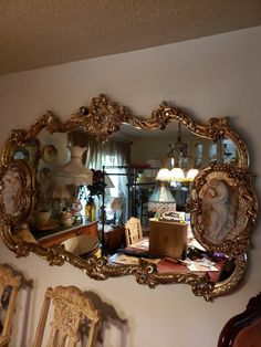 a mirror that is on the wall above a table with chairs and other furniture in front of it