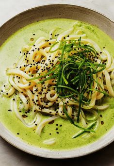 a white bowl filled with noodles and green sauce