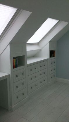 an attic bedroom with white drawers and skylights on the windowsills is shown