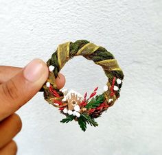 a hand is holding a christmas wreath ornament