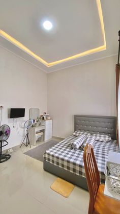 a bed room with a neatly made bed next to a desk and tv on top of it