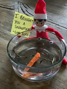 an elf with a sign on his head sitting in a bowl of water holding a carrot