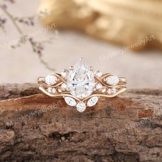 an engagement ring with a pear shaped diamond in the center and leaves on each side