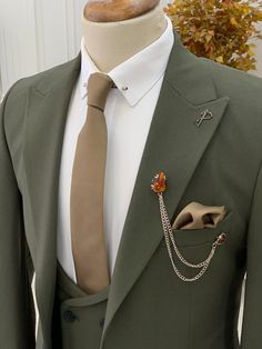 a green suit with a brown tie and an orange brooch on the lapel