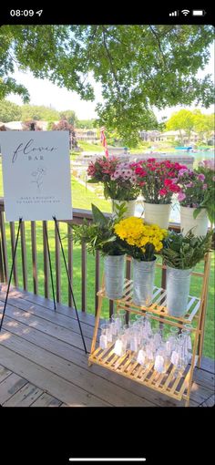 a sign that is on top of a wooden deck with flowers in buckets next to it