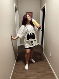 a woman is standing in the hallway and holding a hair dryer up to her face