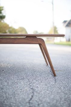 a wooden bench sitting on the side of a road