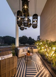 an outdoor living area with couches, tables and lamps hanging from the ceiling above