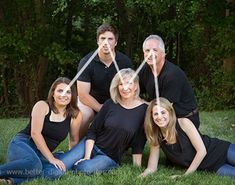 a group of people sitting in the grass posing for a photo with their faces taped to each other