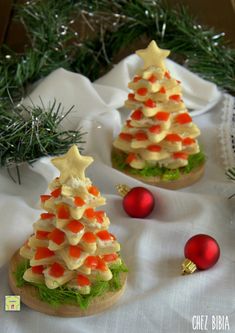 three small christmas trees made out of cookies on a white tablecloth with red and gold ornaments